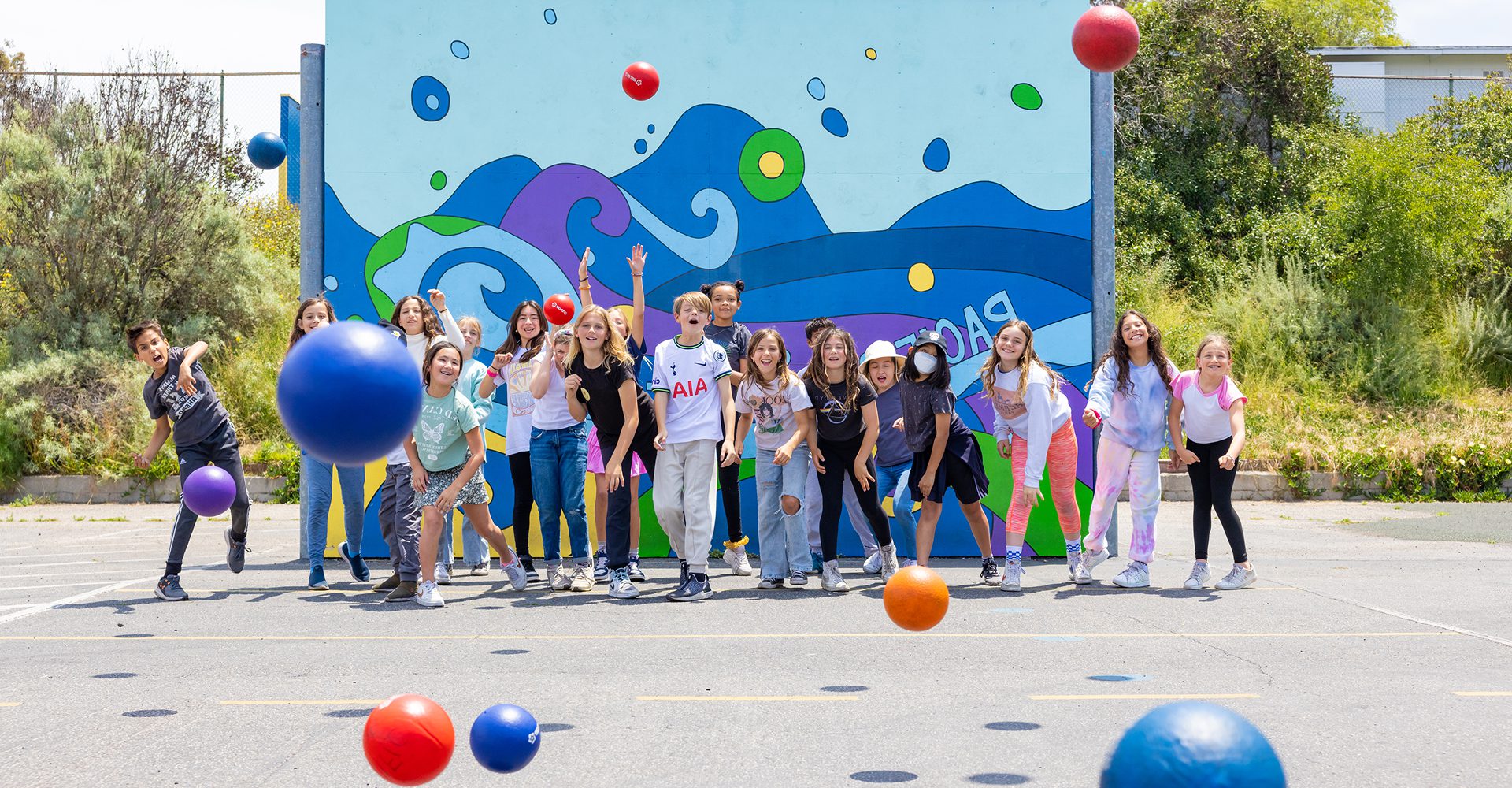 Group of people posing happily in front of a colorful mural outdoors.