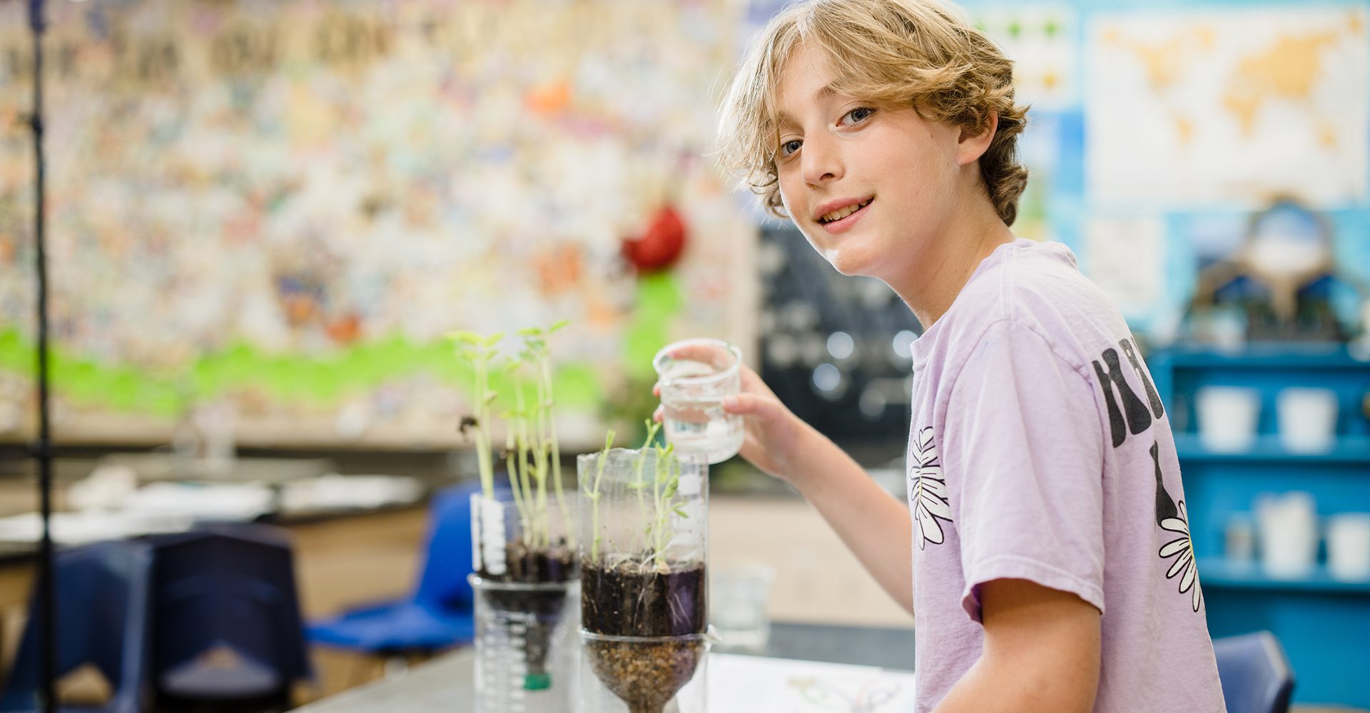 Young boy planting seeds in a small garden setup.