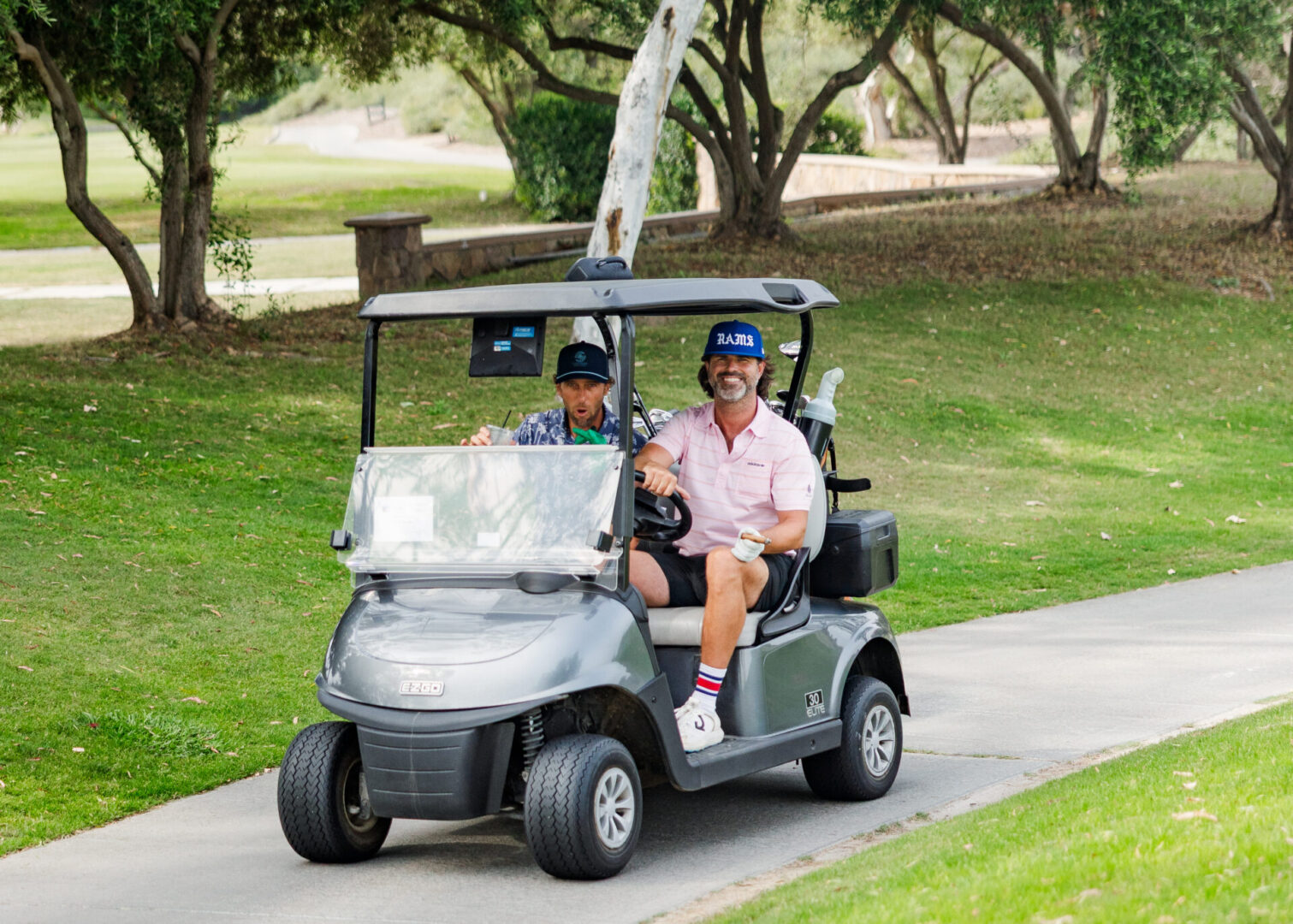 Two men enjoying a golf cart ride.